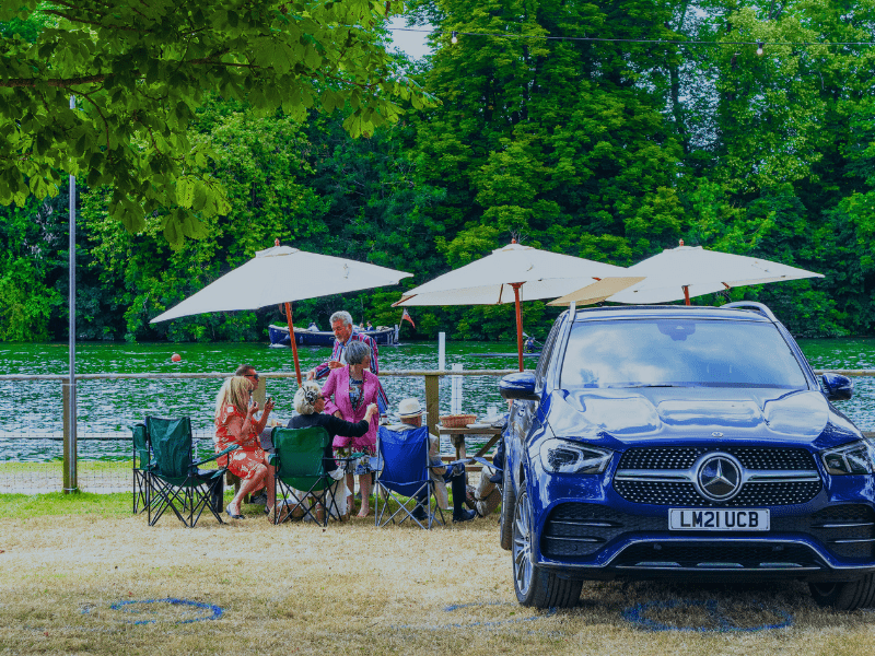 Cars and people by the river having a picnic during Henley Royal regatta