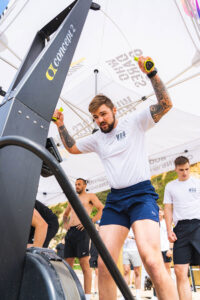 man in white t-shirt works hard at a rowing machine
