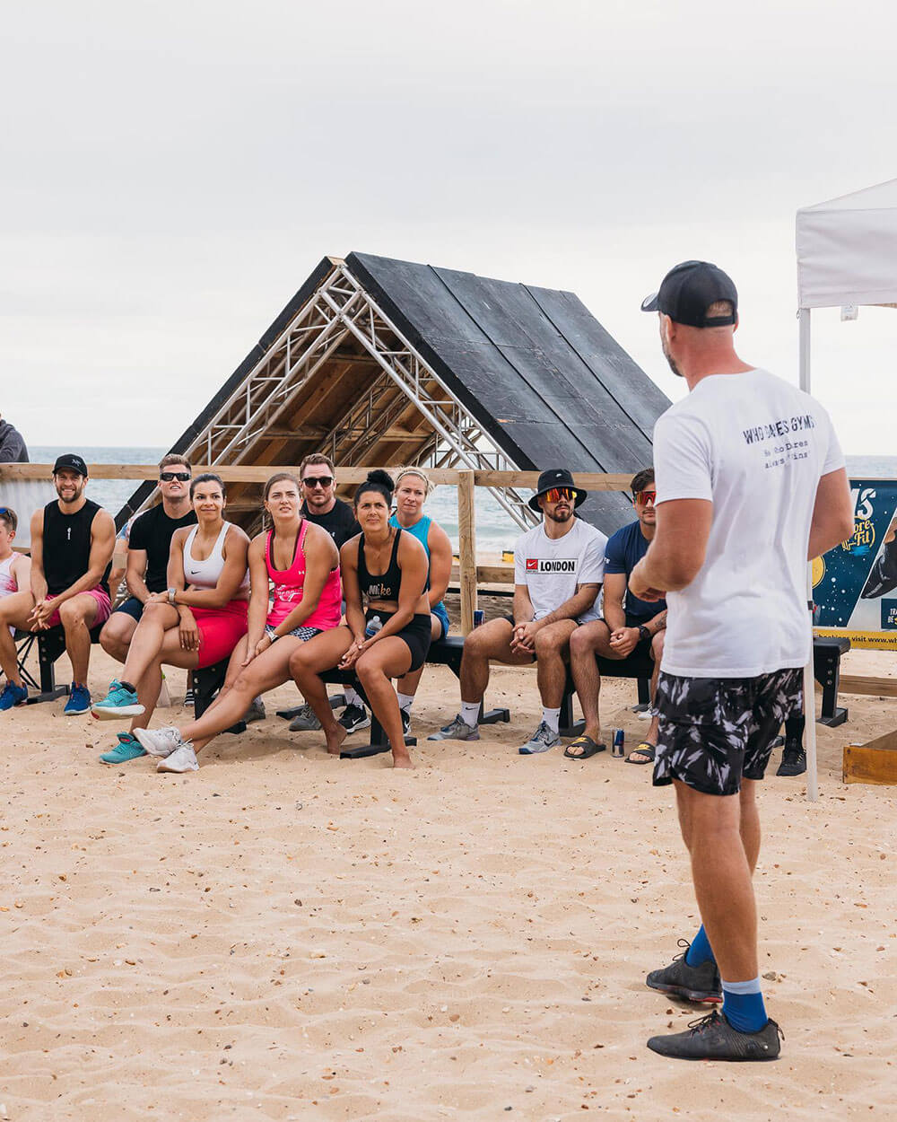GYM INSTRUCTOR STAND IN FRONT OF GOUPR OF PEOPLE ON BEACH