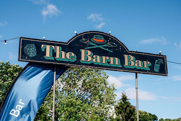 a sign saying The Barn Bar set against a bright blue sky