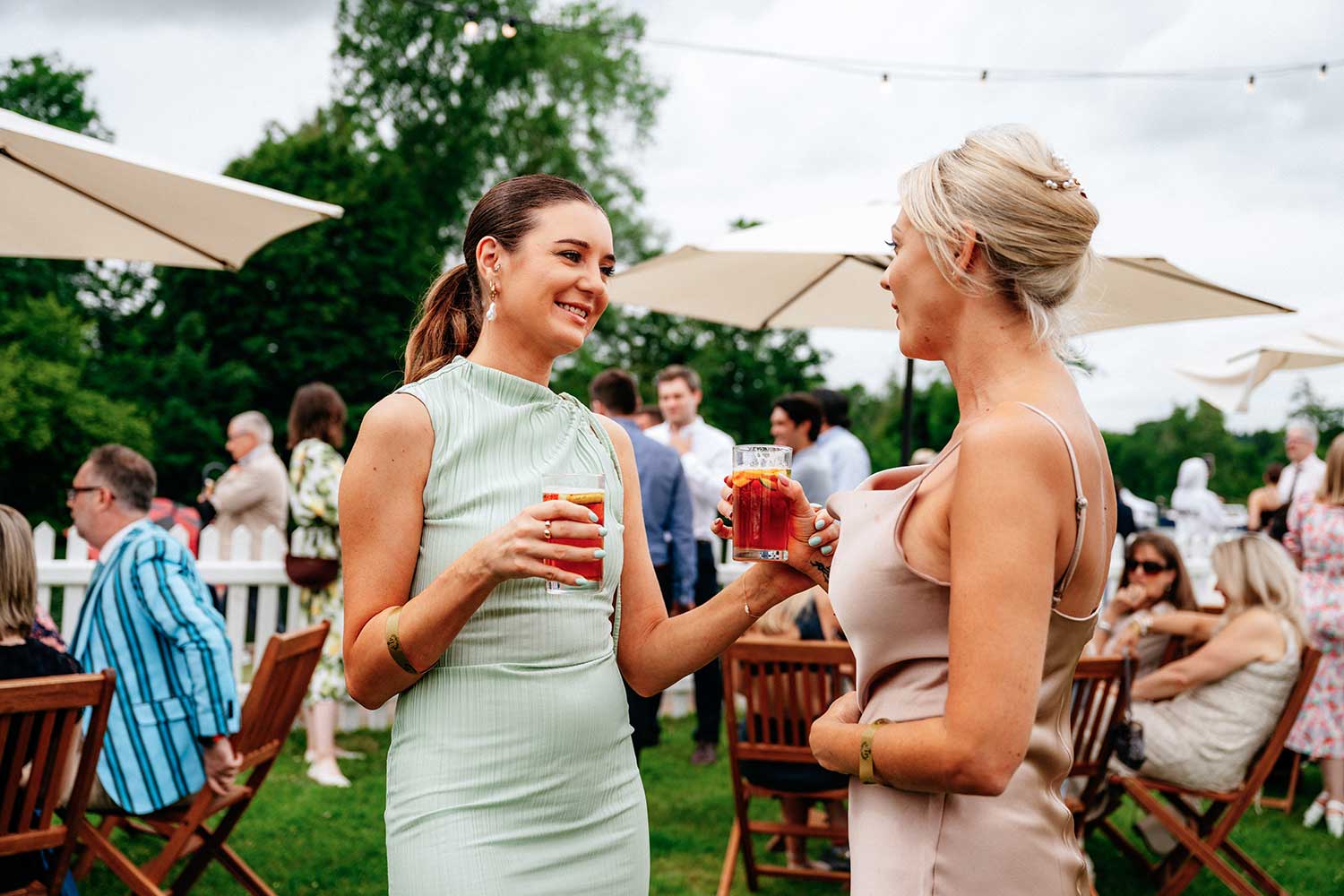 2 women stand and talk over a cocktail