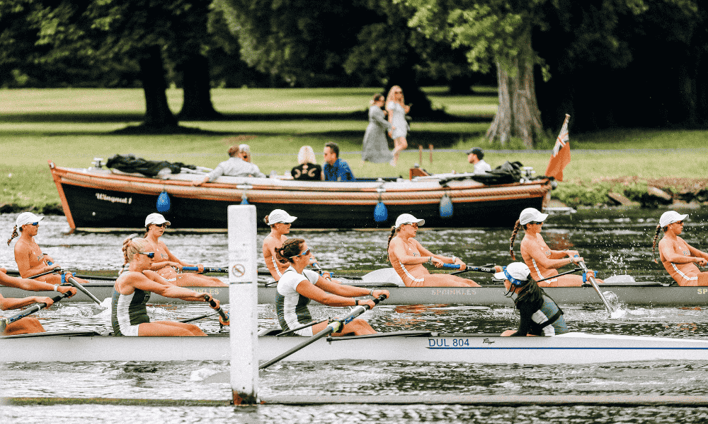 a view acorss a river showing rowers in a rowing boat and a boat in the background