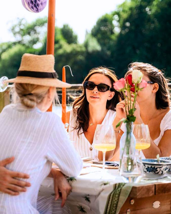 3 people sit at a picnic bench in the sunshine