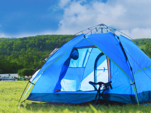 A blue camping tent pitched on grass with the door open, showing the inside of the tent and a small folding chair outside.