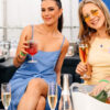 2 women sit with champagne at a table within a marquee