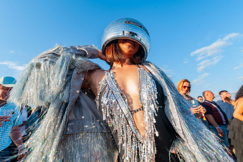 woman in silver catsuit and glitter helmet dancing on a sunny day